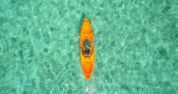 Aerial drone view of a man and woman couple kayaking around a tropical island