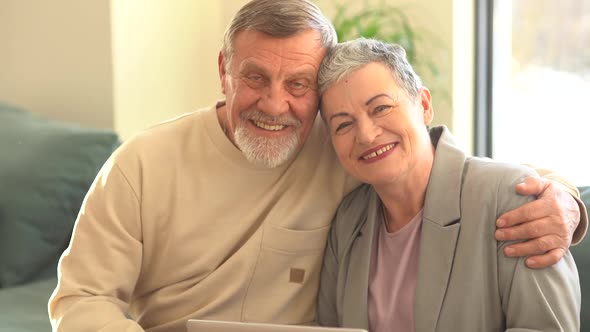 Close Portrait of Smiling Elderly Husband and Wife Looking at Camera