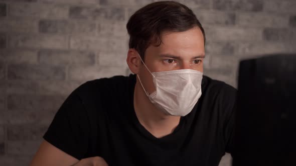 A Man in a Medical Mask Learns News About the Coronavirus From the Internet Using a Laptop