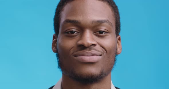 Close Up Portrait of Cheerful African American Guy Smiling To Camera, Blue Studio Background