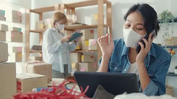 Young Asia businesswomen using mobile phone call receiving purchase order and check product on stock