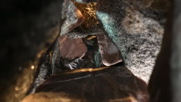 Camera Pans Inside a Pile of Gray and Brown Granite Stones Against a Black Background