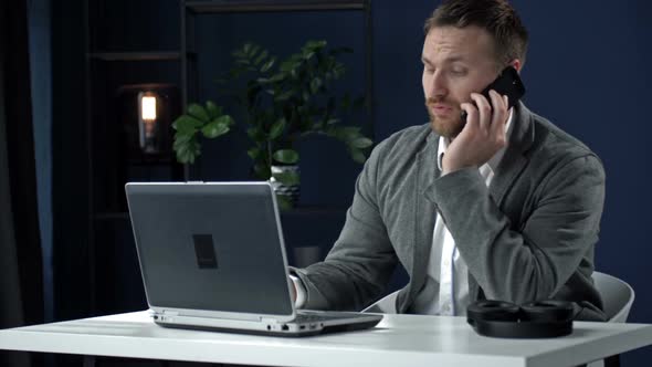 Young Businessman Sitting at the Office Table and Talking with a Partner