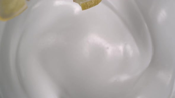 Seven of sliced lemon fall on well crafted fresh yogurt in slow motion