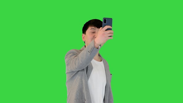 Young Asian Man Walks Making a Video Call on a Green Screen Chroma Key