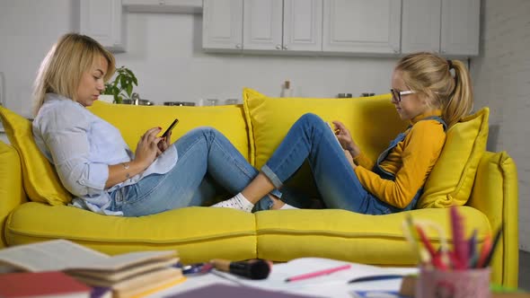 Mother and Daughter on Sofa Using Digital Devices