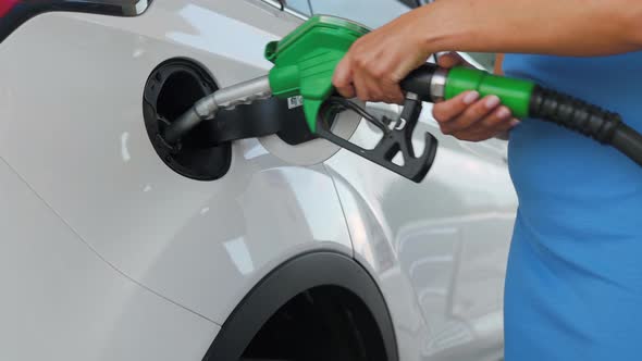 Woman Inserts a Fuel Gun in a Gas Tank To Refuel a Car