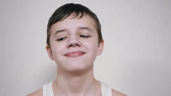 A Smiling Boy with Lowered Eyelids Rotates His Eyes in Different Directions