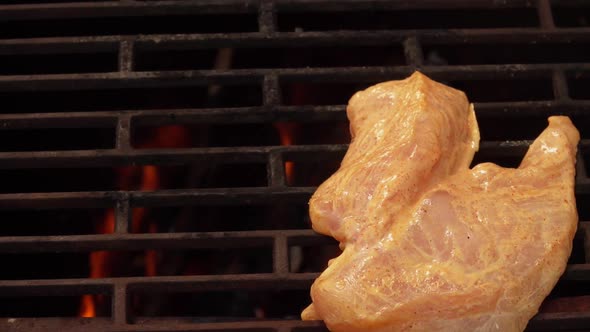 Kitchen Tongs Put Raw Chicken Fillet in the Marinade on the Grill Grid