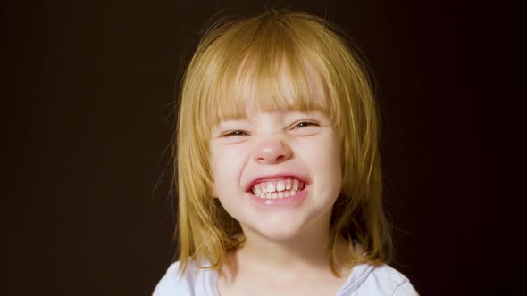 Studio portrait of a cute little blonde girl making excited, happy faces