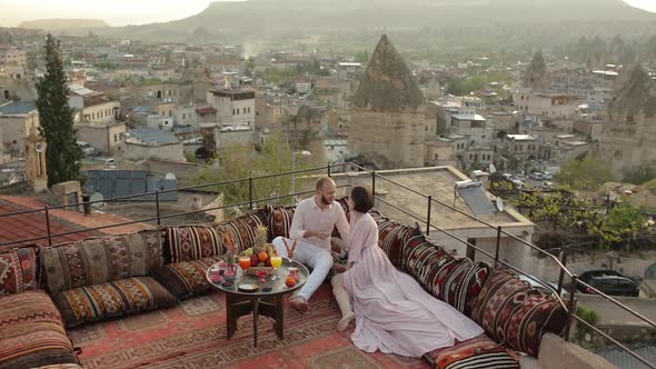 Woman In Dress Seats Near Husband. Romantic Dinner On Rooftop 