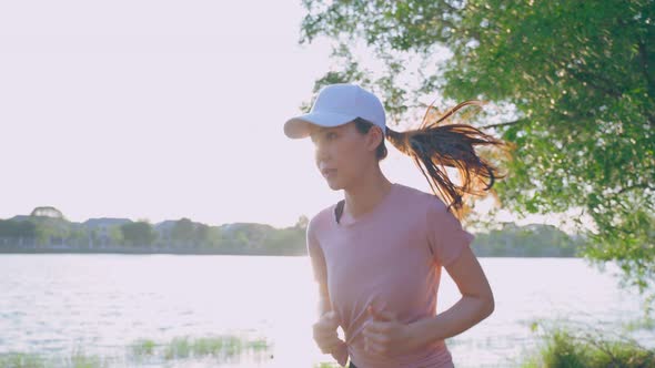 Asian young beautiful sport woman running on street in public park.