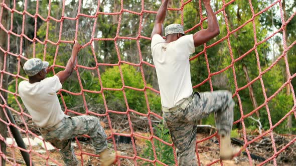 Military soldier climbing rope during obstacle course