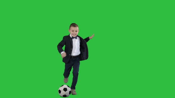 A cute boy in formal suit hitting a ball on a Green Screen