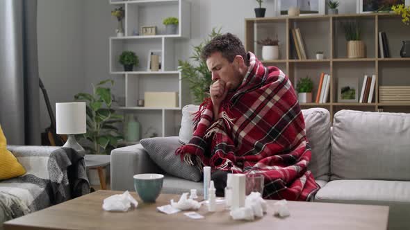 A Man Coughs Heavily While Sitting in a Plaid on a Couch in the Living Room