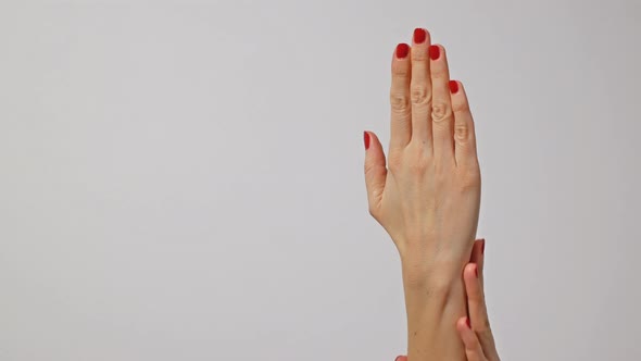 Beautiful Woman's Hands with Bright Red Manicure, One Hand Gently Massaging the Other
