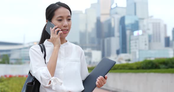 Businesswoman talk to phone and hold with notebook computer