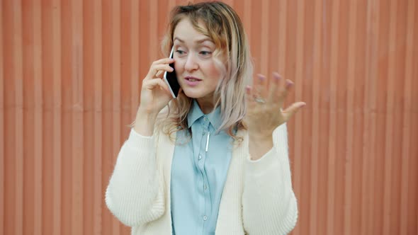 Joyful Young Woman Chatting on Cell Phone Enjoying Gossip Standing Outdoors Alone