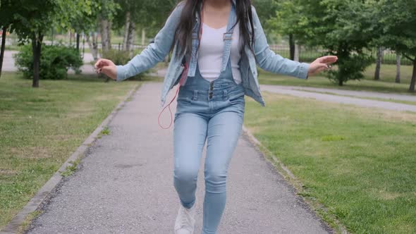 Funny Cheerful Girl Dancing in the Park Listening To Music on Headphones