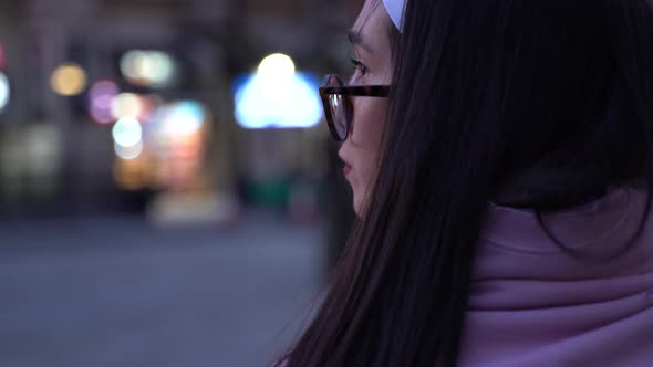 Close up of girl walking in streets alone at dusk, looking at her surroundings.