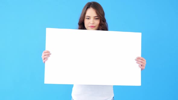 Beautiful woman holding blank placard on blue background