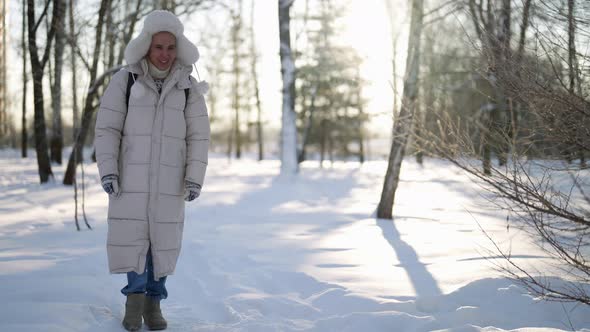 Young Man is Walking in Forest in Sunny Winter Day Enjoying Good Frosty Weather