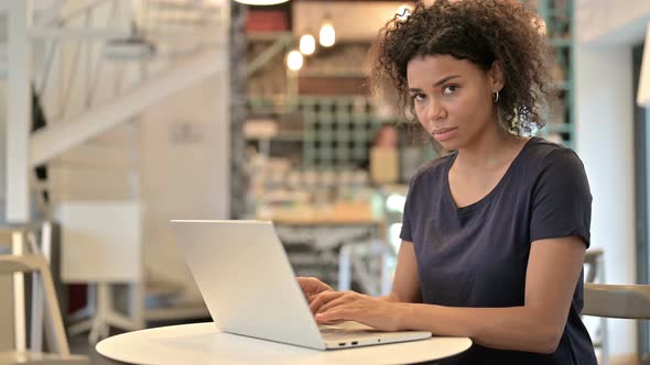 Laptop Use By Young African Woman Smiling at Camera in Cafe 