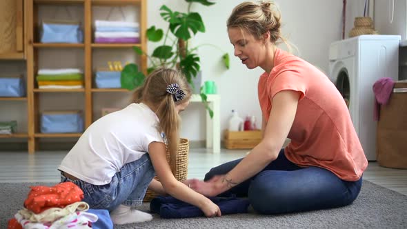 Mom and Daughter Do Household Chores and Have Fun Sits in Home Laundry Spbd