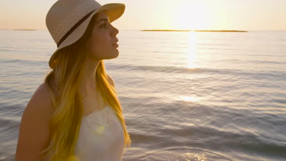 Steadycam shot of a Young attractive woman walking on the beach during sunset