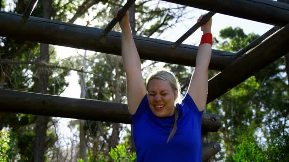 Determined woman exercising on monkey bar during obstacle course