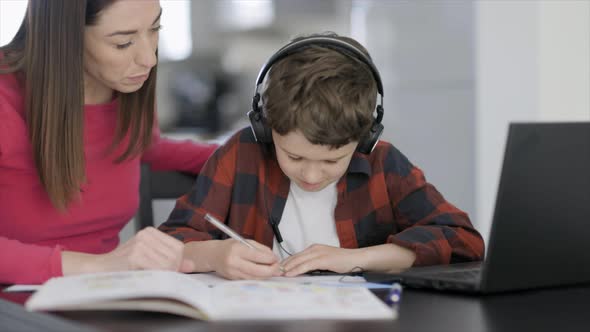 Mother helping son with homework on laptop