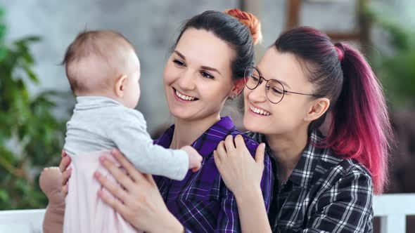 Happy Female Parents Holding Little Son Playing and Admiring Cute Baby Medium Closeup