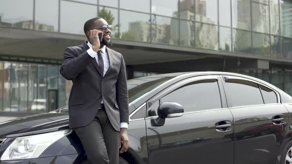 Afro-American Man Talking on Phone With Smile on Face Near Office