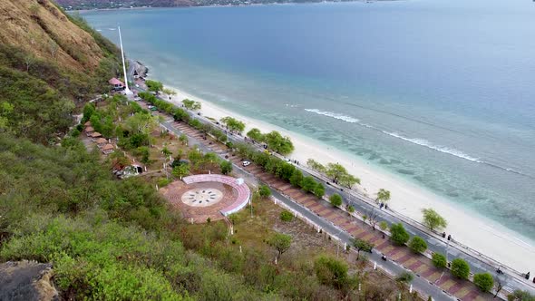 Aerial drone rising over stunning shoreline, white sandy beach, blue ocean at the popular gathering