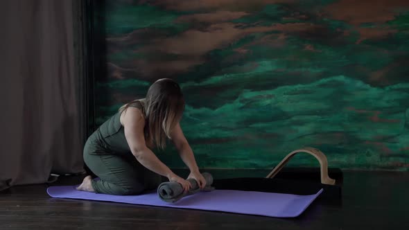 a Woman in a Green Jumpsuit is Sitting on Knees on a Sports Mat