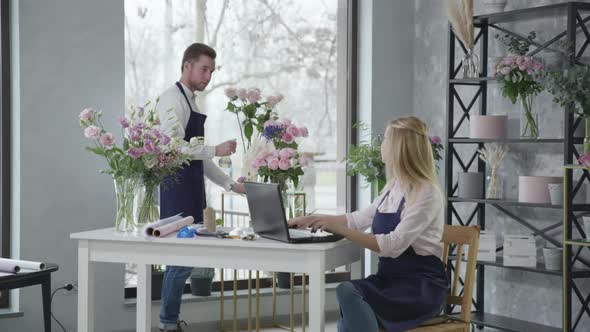 Flower Shop, Young Specialist Girl Together with Employee Takes an Order To Deliver Bouquet 