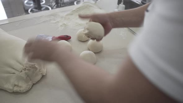 Professional Baker Making Dough Balls From a Large Piece of Raw Dough