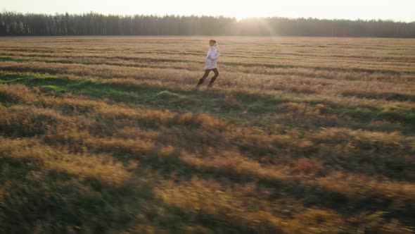 Teenage Girl Running Across the Field in Front of the Setting Sun