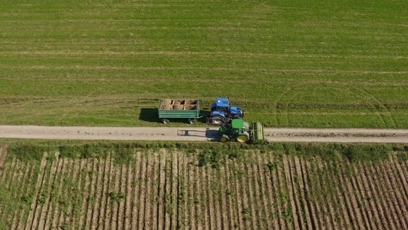 At the field - one agracultural modified tractor is passing by a potatoe collecting one, with a pull