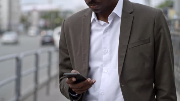 African Businessman Texting on Smartphone while Standing on Street