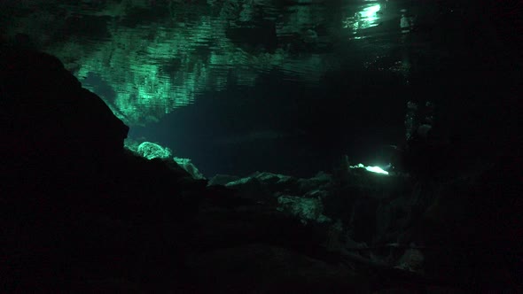 Scuba Divers in Cave system Cenote Tajma Ha in Yucatan Mexico and reflection on water surfacce