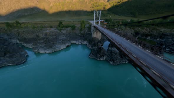 Aerial View Flying Bridge Over Natural Mountain River with Walking People and Camping Automobile