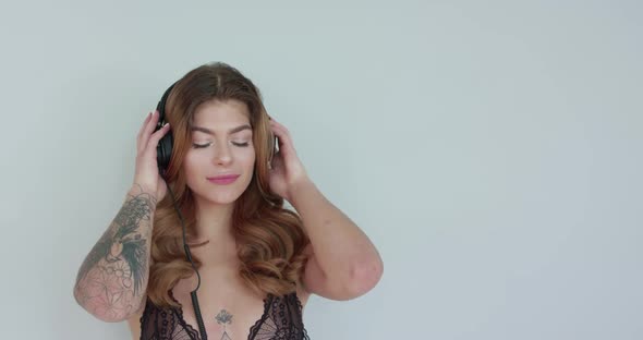 Woman Puts Headphones Over Her Ears Reacts to the Music and Subtely Sways Along