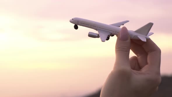 Airplane Model in a Female Hand in the Background Sky During Sunset