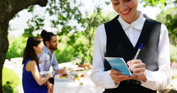 Waitress writing on note pad at outdoor restaurant