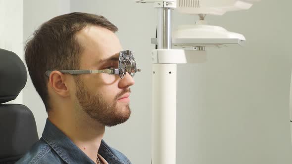 Consultant in the Optics Salon Helps a Young Man To Choose the Right Glasses for Vision