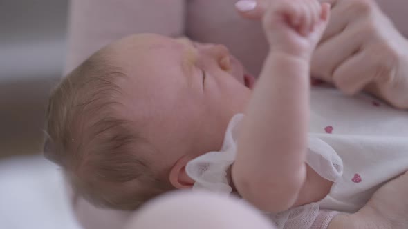 Crying Infant in Hands of Unrecognizable Woman Touching Baby Nose Trying Calm Down Child