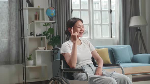 Asian Woman Sitting In A Wheelchair Thinking About Something Then Raising Her Index Finger