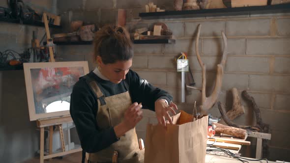 Smiling carpenter packing order in paper bag