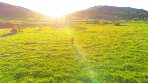 Flight Over Sport Man at Perfect Green Grass Meadow. Sunset in Mountain